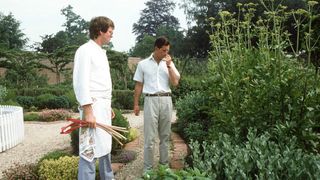 King Charles smelling herbs as he walks around the garden at Highgrove House with his chef