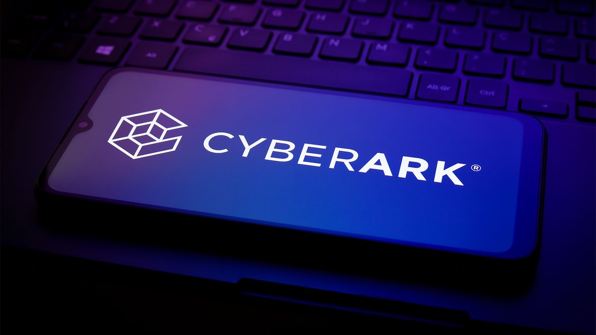 CyberArk logo and branding pictured on a smartphone screen placed on a desktop computer keyboard.