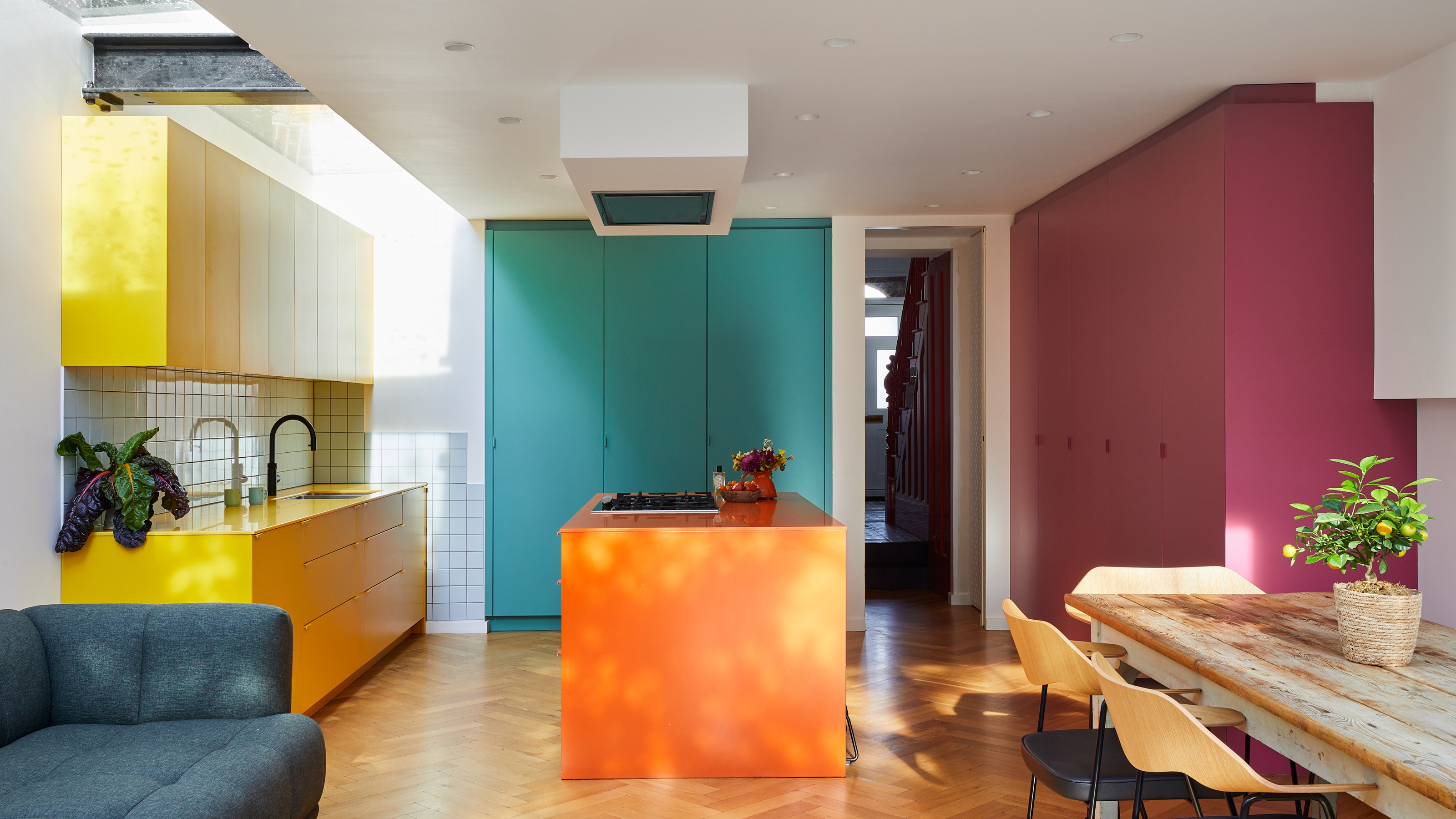 a color blocked kitchen with an orange island, yellow, teal and red cabinets