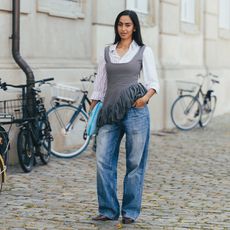 Woman wears jeans whit button down and tank top with fringe hem. 
