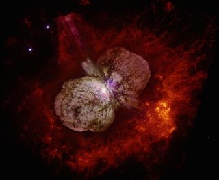 A color image from the Hubble Space Telescope of the Eta Carinae star system surrounded by a dumbbell-shaped cloud of gas and dust. The star system ejected more than 10 times the mass of the sun's worth of gas and dust during an enormous eruption in the 1800s. Researchers think the interactions of a three-star system could have caused the blast and left a surviving star system.