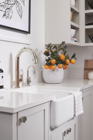 A white kitchen with a rose gold and nickle faucet