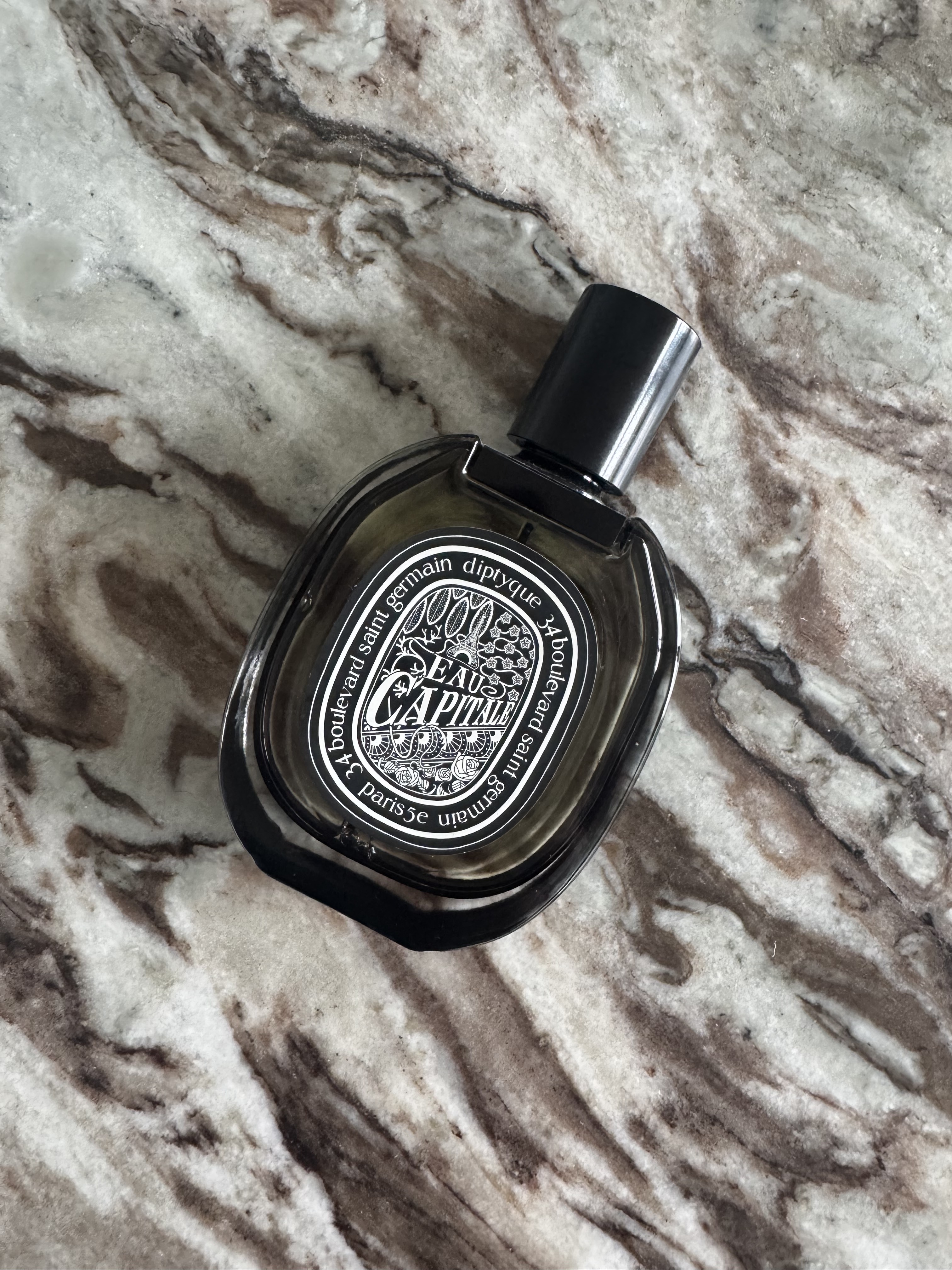 A bottle of Diptyque Eau de Capitale on a marble table