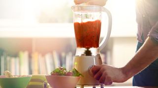 A blender being used to make a red smoothie