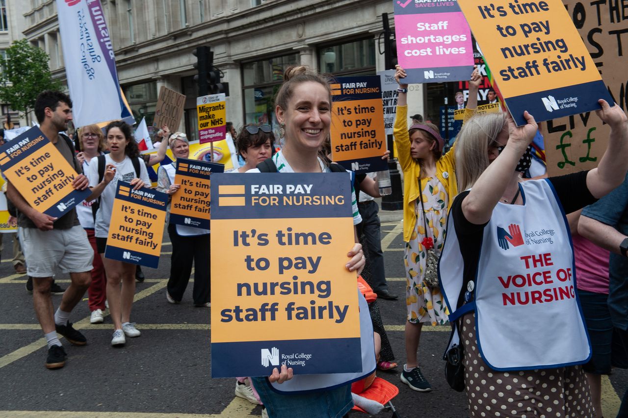 A protester holding a placard saying &#039;Fair Pay for Nurses&#039;