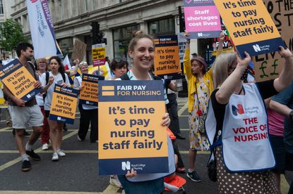 A protester holding a placard saying 'Fair Pay for Nurses'
