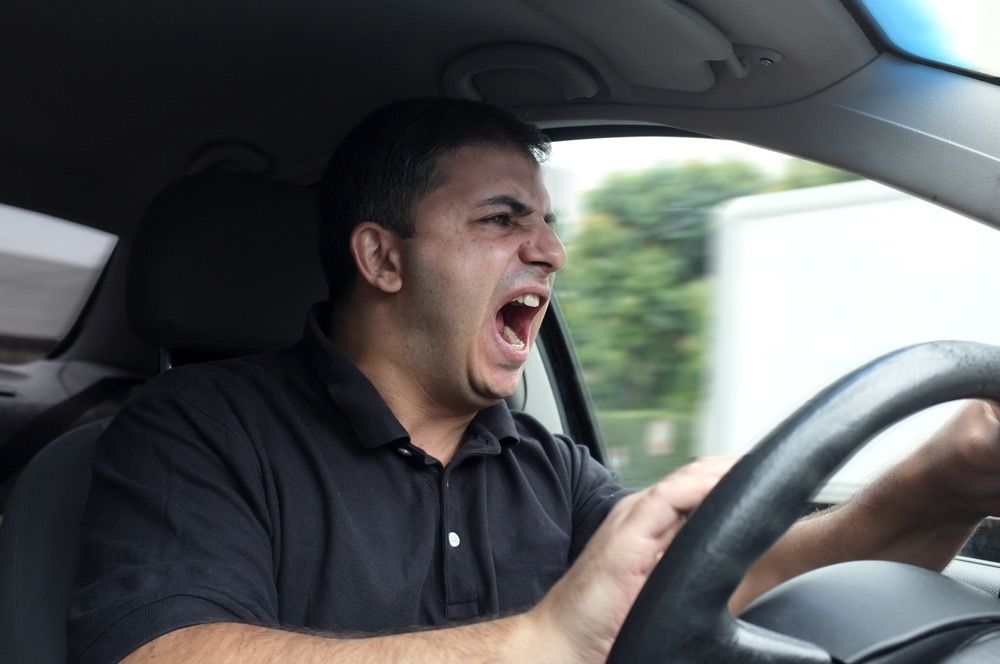 Angry man driving a car without a seatbelt.