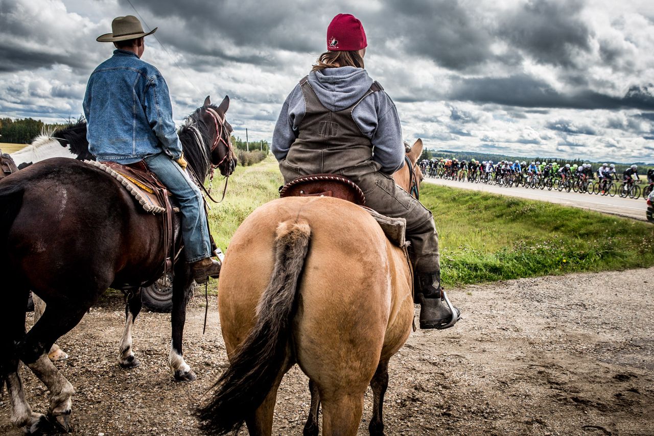 Horses and ranchers watch as the race rolls past during stage 3 at the Tour of Alberta