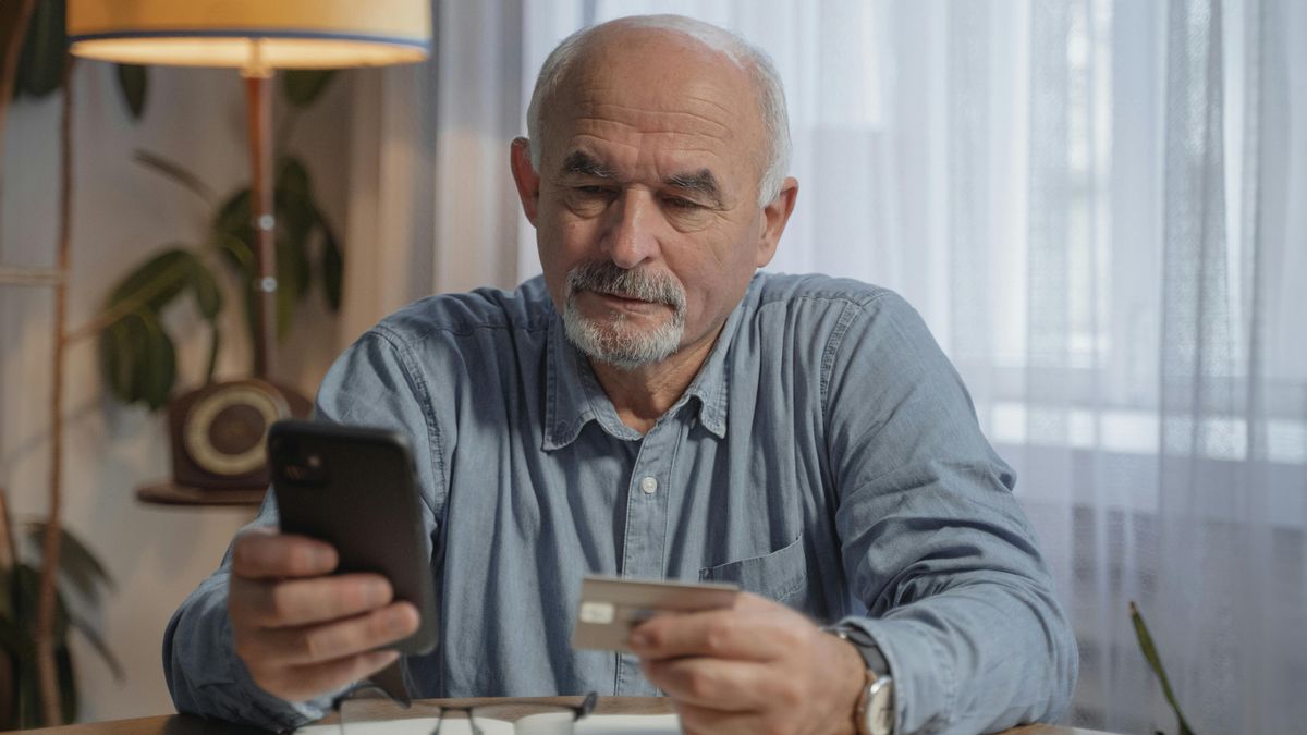 Man looking at credit card and phone screen