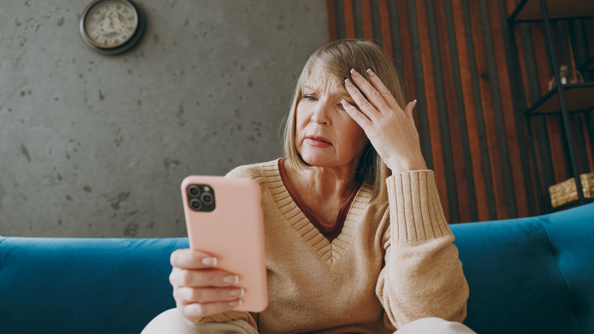 An older woman holds a smartphone looking confused
