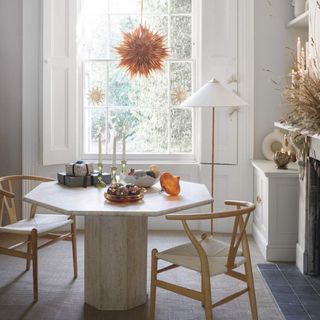 A bright dining area minimally decorated for Christmas with a hexagonal stone dining table and wishbone chairs