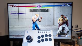 Hori Fighting Stick Mini held in front of monitor playing Street Fighter 6