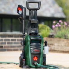Bosch Aquatak pressure washer in promotional image being used in garden