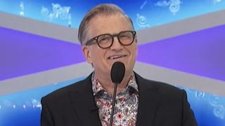 Drew Cary talking into mic hosting Price is Right episode