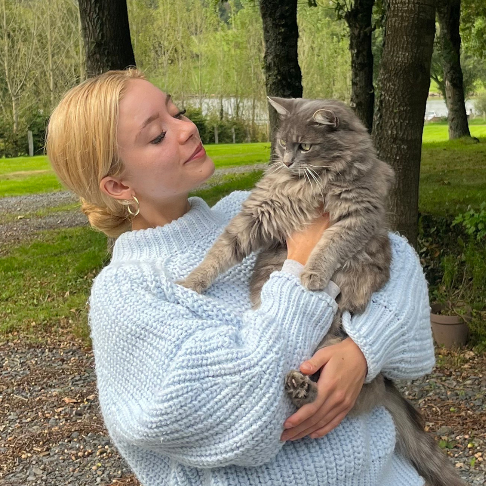 Megan Milstead holding a grey cat in the garden