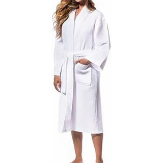 A tanned woman with long hair wearing a white cotton bathrobe. 