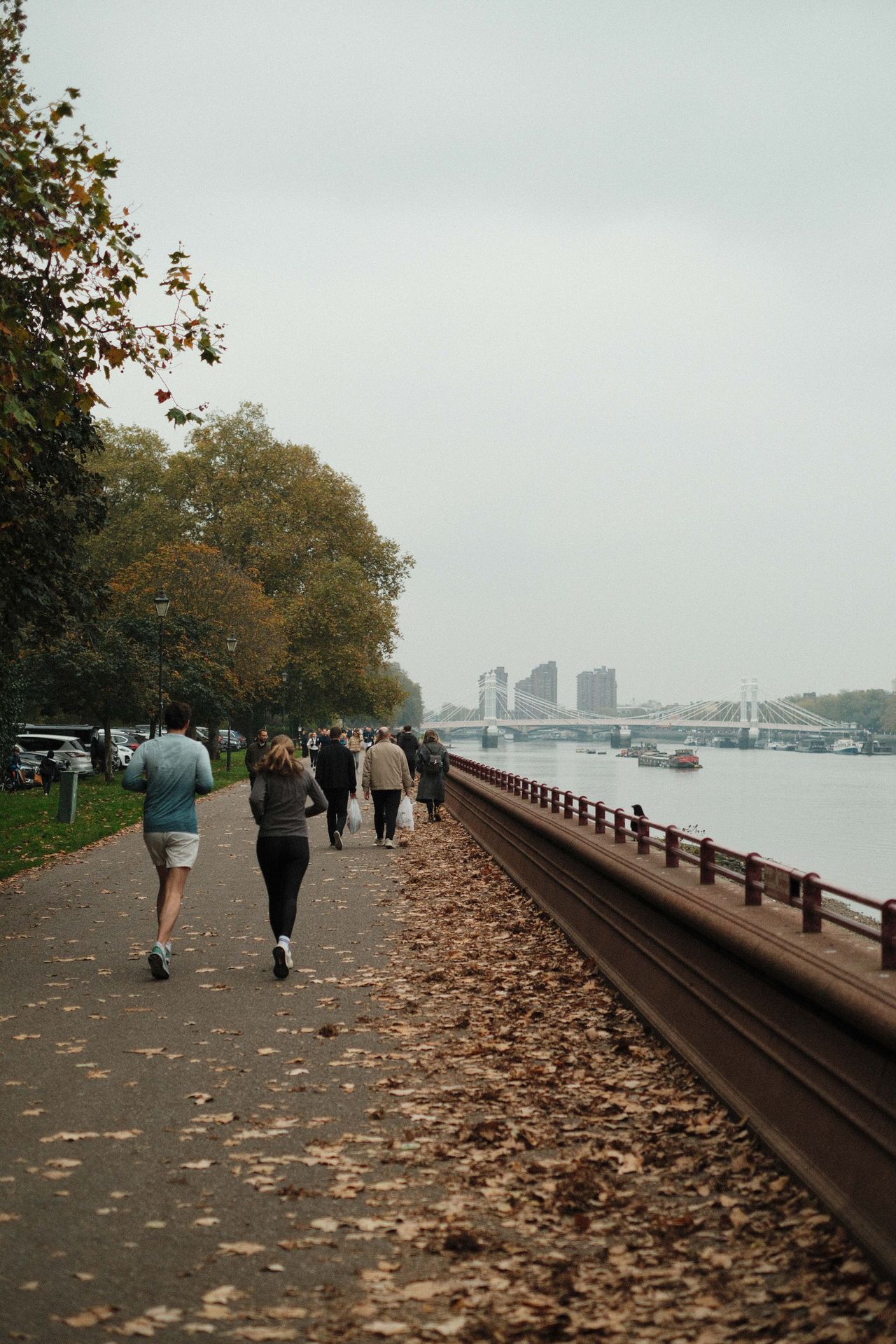 Runners on a riverside path in Battersea park on a very overcast day