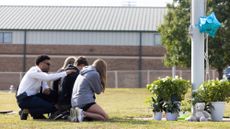 Students kneel in front of a memorial following a mass shooting at Apalachee High School in Winder, Georgia.