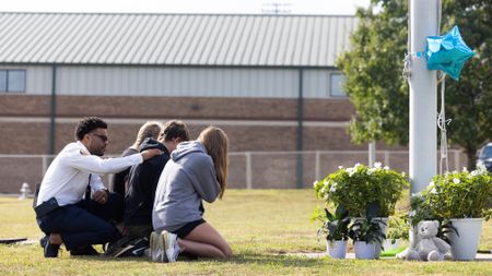 Students kneel in front of a memorial following a mass shooting at Apalachee High School in Winder, Georgia.