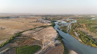 An aerial view of a river through a desert area with some vegetation