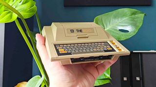 Hand holding Atari 400 Mini console with plant in backdrop