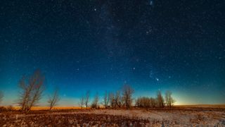 a starry night sky above a snow-covered field