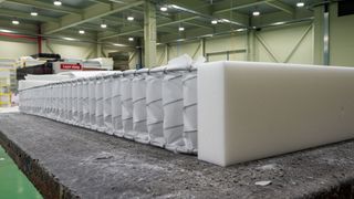 Image shows the coil layer inside a hybrid mattress being made in a factory