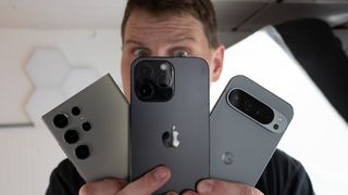 Looking at an iPhone 14 Pro Max, Samsung Galaxy S24 Ultra, and Google Pixel 9 Pro XL with a worried expression