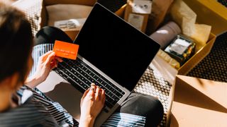 Young woman making payment with credit card while doing subscription shopping via laptop