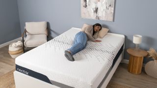 A woman lies on her side on the Nectar Luxe mattress in a blue bedroom