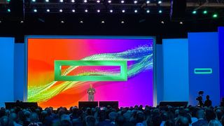 HPE CEO Antonio Neri onstage at HPE Discover Barcelona 2024, with a huge screen behind him displaying the HPE logo set against a red, purple, and blue background.