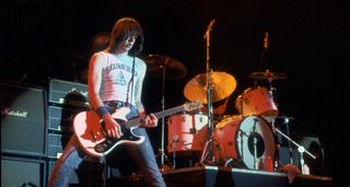 Johnny Ramone plays a low-slung Mosrite onstage with the Ramones, a bank of Marshall amps in the background