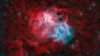 A nebula rages in space with brilliant hues of red and blue.