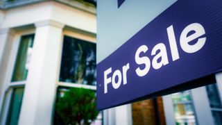 Exterior of house with bay window and for sale sign