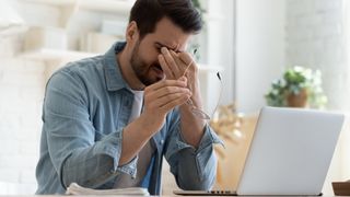 Person with eye strain working on laptop