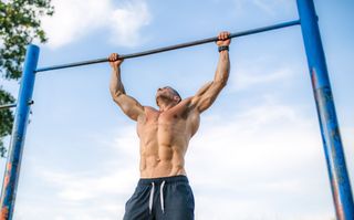 Man hanging from a pull-up bar during outdoor workout