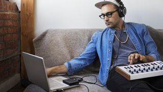 Man records a synth into a laptop with an external hard drive connected