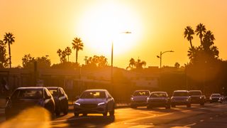 cars drive on a freeway under a bright orange sun