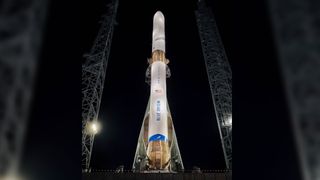 a rocket in between launch towers and surrounded by night sky