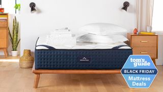 DreamCloud mattress on a wooden bed frame, in a bedroom scene, with folded sheets and two pillows on top