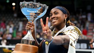 Coco Gauff holds a trophy in one hand and displays the peace sign with the other after winning the Auckland Classic tennis tournament in 2024