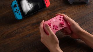 A marketing image of the 8BitDo Ultimate 2C in pink playing a Nintendo Switch