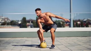 Man outdoors training holding a kettlebell in right hand 