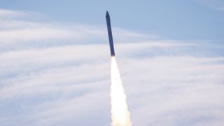 a white rocket lifts off into a clear blue sky