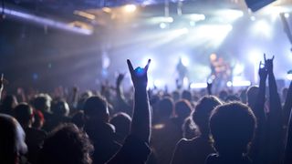 Best earplugs for concerts: Crowd at a rock concert with stage in the background blurred