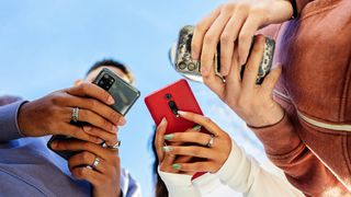 Low angle view of three young people using mobile phones outdoors