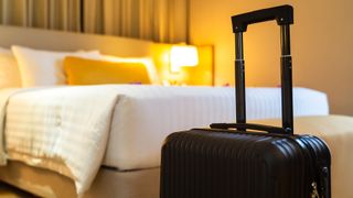 Suitcase next to a hotel bed