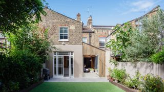 exterior view of terraced property with small kitchen extension to rear, one section finished in redner, the other timber clad with large opened picture window