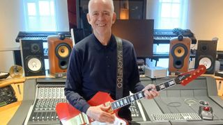 A photo of Phil Manzanera in his studio holding his Cardinal Red 1965 Gibson Firebird VII. Photographed in 2024