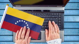 Woman&#039;s hands and flag of Venezuela on computer, laptop keyboard